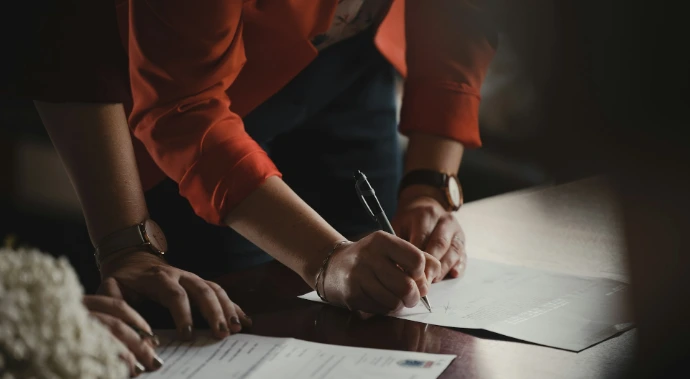 person in orange long sleeve shirt writing on white paper